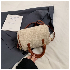 Detail of faux shearling texture and brown leather strap on cylindrical boston bag