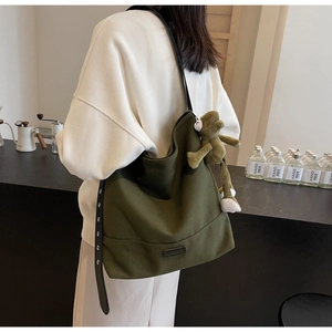 Detail of olive green canvas tote bag with black strap and cute green frog pendant charm
