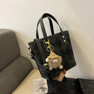 Dettaglio borsa tote grigia trapuntata a rombi con rivetti dorati e ciondolo peluche