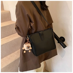 Vue latérale d'un sac bandoulière en cuir noir avec charm mouton en peluche sur un mannequin