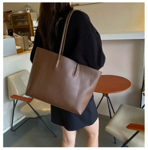 Detail shot of a large brown leather tote bag with long straps for commute and daily use