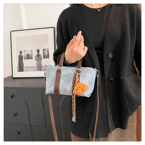 Detail of vintage denim textured mini bag with brown handle and plush bear charm