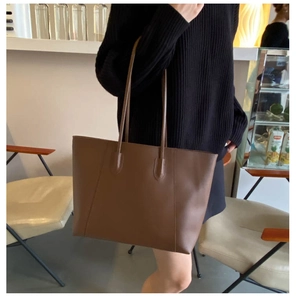 Detail view of the brown leather tote bag showing smooth matte texture and stitching