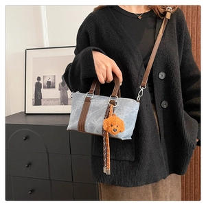 Detail of vintage grey-blue crossbody pillow bag with plush dog charm and leather strap
