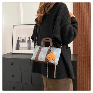 Detail of vintage Boston bag with blue washed fabric and cute orange plush dog charm