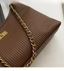 Detailed close-up of dark brown pleated leather texture and golden metal chain link