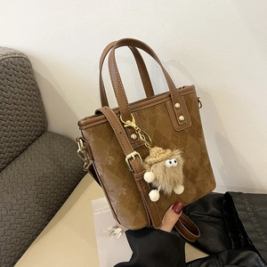 Dettaglio borsa a secchiello marrone vintage con texture trapuntata e ciondolo peluche