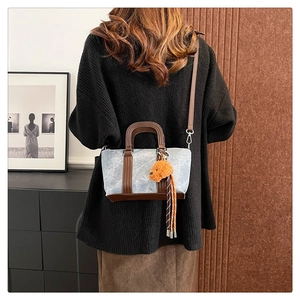 Model showing a vintage blue marble pattern handbag with plush dog charm and tassels