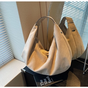 Detail of beige suede hobo tote bag showing soft texture and metal hardware accents