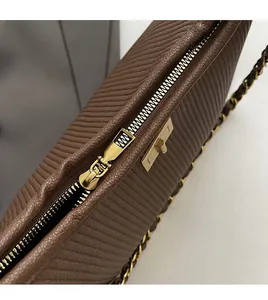 Detail of wave-textured brown leather bag with golden metal zipper and chain strap