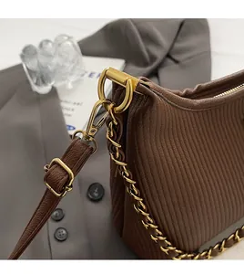 Detail of a brown pleated texture shoulder bag showing the golden metal hook and chain