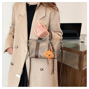Detail of vintage brown satchel with plush bear charm and textured leather finish