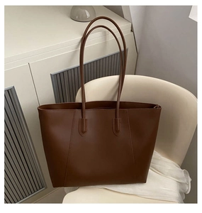 Detail view of the brown minimalist tote bag on a chair showing the slim dual straps