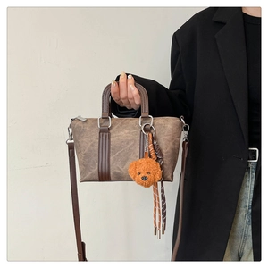 Detailed view of a vintage brown doctor bag with a cute plush charm and crossbody strap