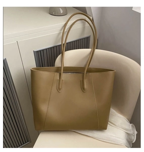 Detail shot of a khaki minimalist large tote bag placed on a white designer chair