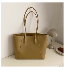 Detail of light brown leather tote bag with stitching on a minimal lifestyle desk setup