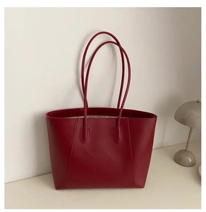 Detail view of smooth dark red leather tote bag with minimalist vertical stitching detail