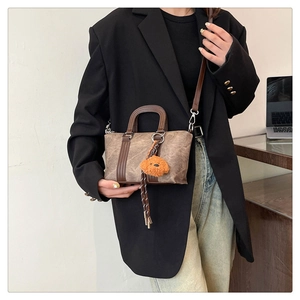 Detail view of a vintage brown Boston bag featuring a plush bear charm and crossbody strap