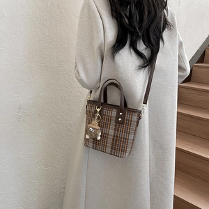 Dettaglio della borsa tote vintage a quadri con ciondolo di peluche e tracolla in pelle