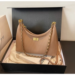 Close-up of light brown pleated leather shoulder bag with gold twist lock in a gift box