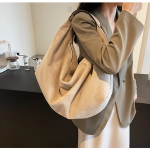 Detail of beige suede hobo bag with zip closure shown in a modern cafe setting