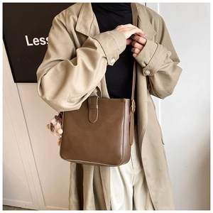 Détails d'un sac seau en cuir mat marron foncé avec une bandoulière réglable chic