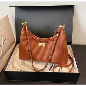 Close-up of brown pleated shoulder bag with gold turn-lock in elegant gift box