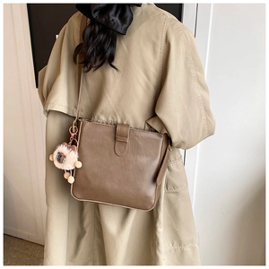 Détail d'un sac seau en cuir PU marron avec un porte-clés décoratif en peluche douce