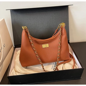 Detail of dark brown pleated leather shoulder bag with gold chain strap in premium gift box