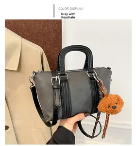 Detailed view of a grey matte bucket bag with a brown plush bear pendant and silver hardware