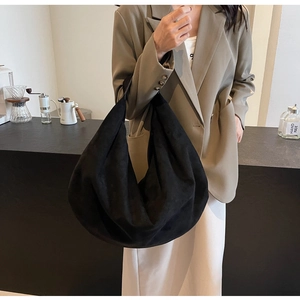 Détail d'un sac hobo en daim noir avec bouton en métal dans un café au style moderne