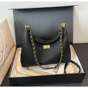 Detail of black pleated leather bag with gold clasp and chain strap in gift box