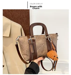 Detail of vintage brown canvas bucket bag with leather strap and cute dog charm