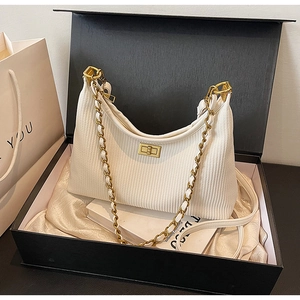 Detailed macro view of white pleated fabric texture and golden metal twist lock on a handbag