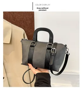Detail of grey canvas bucket bag with black leather straps and silver metal zipper