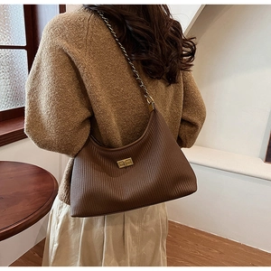 Detail of dark brown pleated shoulder bag with gold metal buckle and leather chain strap