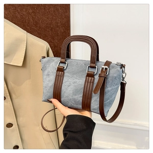 Detail of blue denim fabric and brown leather handle with metallic hardware buckle