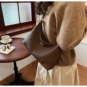 Detailed view of brown pleated crescent bag with gold buckle on a stylish model