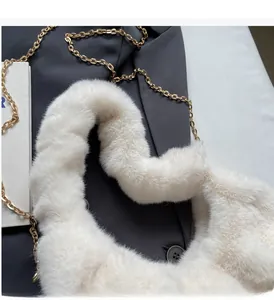 Close-up of white faux mink fur handle with elegant gold chain on soft cloud bag