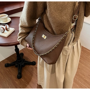 Detail showing deep brown pleated leather bag with gold chain and crossbody strap