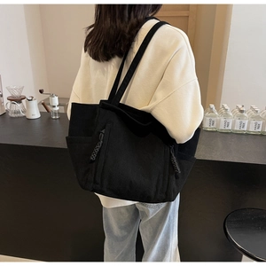 Dettaglio della borsa tote in velluto nero con tasca laterale e cerniera intrecciata