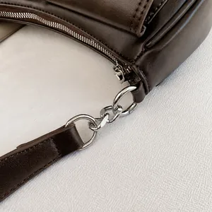 Detailed close-up of dark brown leather texture and silver chain strap connector on the bag