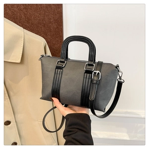 Detail of a gray crossbody pillow bag with black leather straps and silver hardware