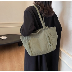 Dettaglio borsa tote in velluto a coste verde con tasche a zip e tiranti in corda intrecciata