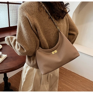 Detail view of khaki pleated shoulder bag featuring gold twist lock and woven chain strap