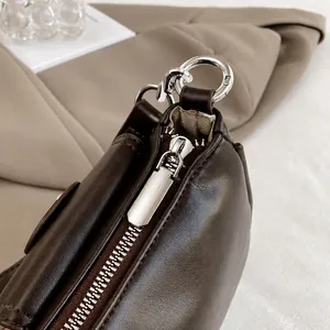 Detailed close-up of a dark brown leather handbag with a smooth silver metal zipper