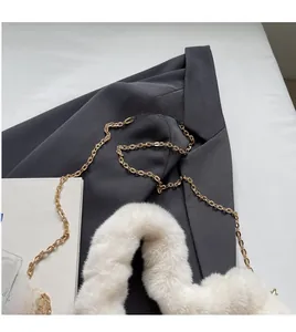 Detailed close-up of white plush strap and elegant golden metal chain link of the handbag