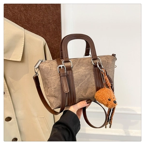 Detail of vintage brown crossbody bag with a plush teddy bear charm and leather strap