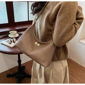 Close-up of pleated brown chain hobo bag with a gold twist lock on a wooden cafe table