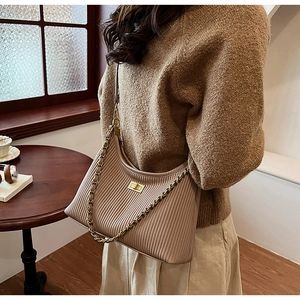 Detail of pleated shoulder bag with gold twist lock and leather chain strap on model